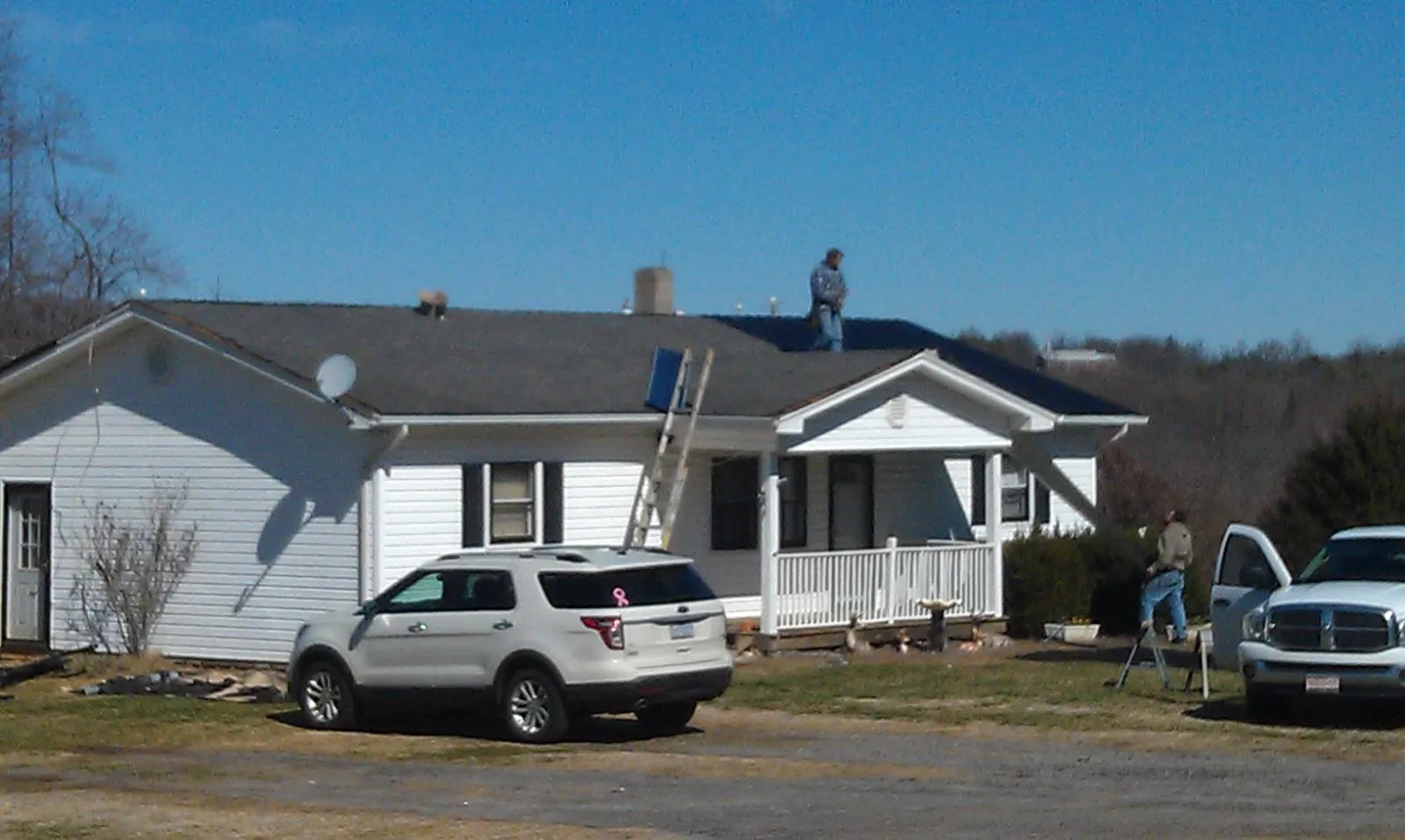 Roofers stripping shingles from a white ranch house roof in Stanley